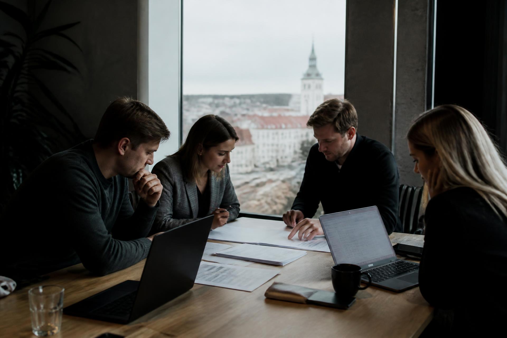 A small business team reviewing documents and laptops around a table in a modern European office